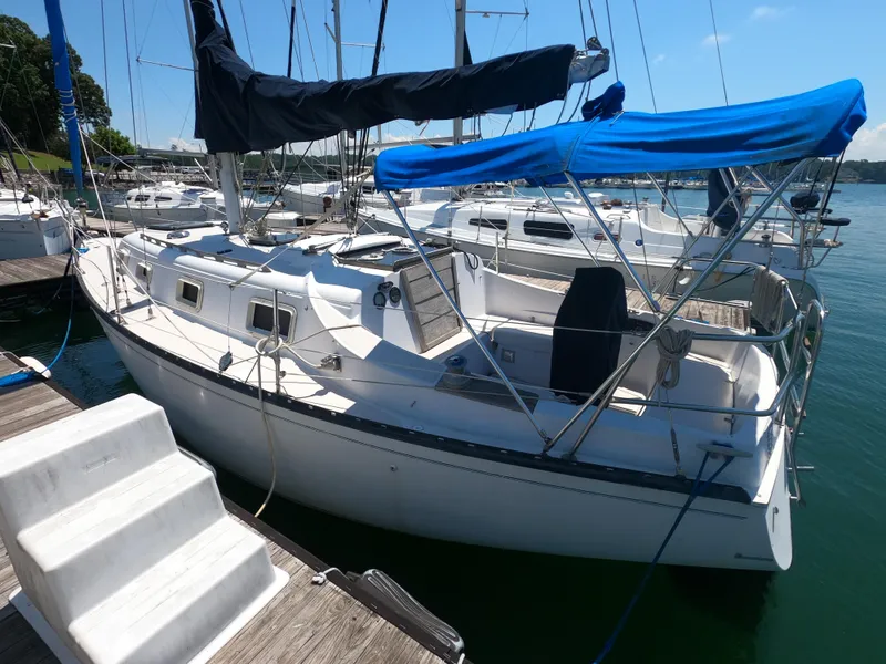 Slide: The Image of 1979 Hunter 30 sailboat docked at marina, featuring blue canopy and white hull. - 2