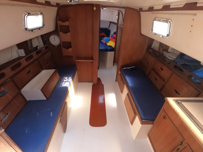 Slide: The Image of Interior of a 1979 Hunter 30 sailboat with wooden cabinetry and blue cushions. - 7