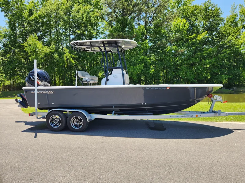 The Image of 2023 Sportsman Masters 227 Bay Boat on trailer, parked outdoors with lush green background. - 0
