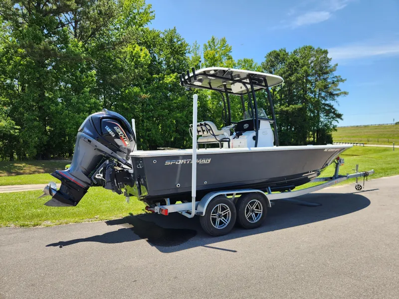 Slide: The Image of 2023 Sportsman Masters 227 Bay Boat on trailer, parked outdoors with trees in background. - 2