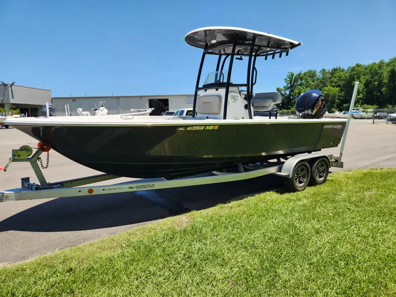 Slide: The Image of 2023 Sportsman Masters 227 Bay Boat on trailer, parked on grass under clear blue sky. - 5