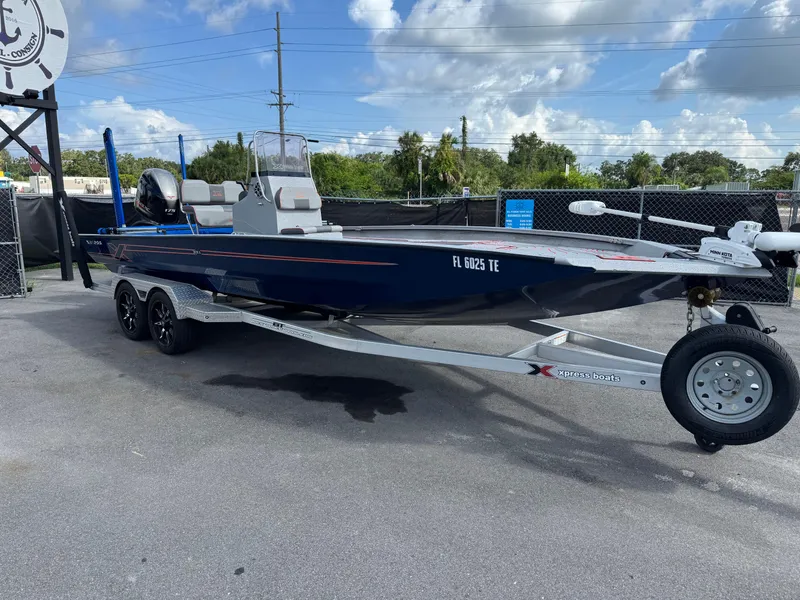 Slide: The Image of 2022 Xpress H24B boat with blue canopy on a trailer, parked outdoors. - 0