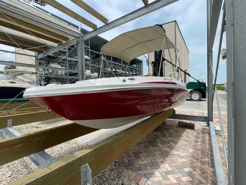 Slide: The Image of 2021 Hurricane SunDeck Sport 185 OB boat in dry dock, red hull, covered canopy. - 3