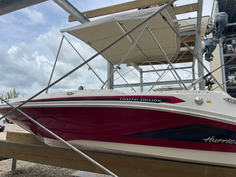 Slide: The Image of 2021 Hurricane SunDeck Sport 185 OB Coastal Edition boat on a lift, under cloudy sky. - 6