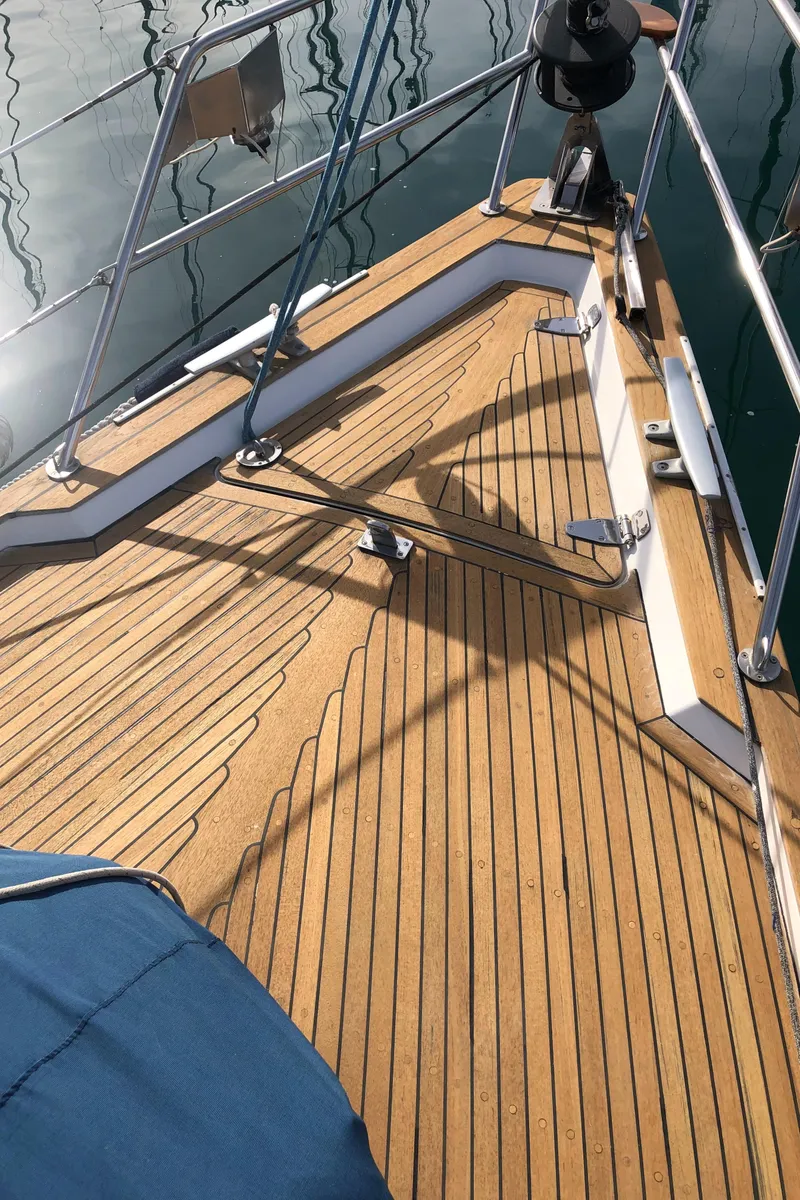 Slide: The Image of Teak deck of a 2001 Malo 43 sailboat, featuring polished wood and metal railings. - 33