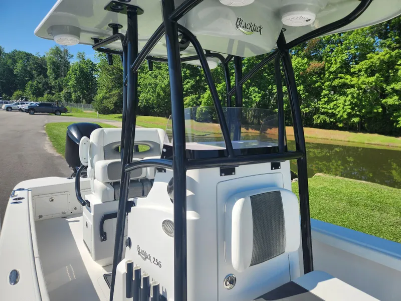 Slide: The Image of 2021 BlackJack 256 Coastal boat interior with seating and console, parked near a pond. - 10