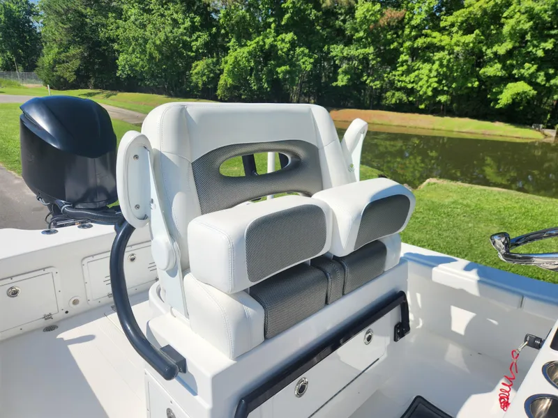 Slide: The Image of 2021 BlackJack 256 Coastal boat seat with dual cushions, near a serene waterway. - 15