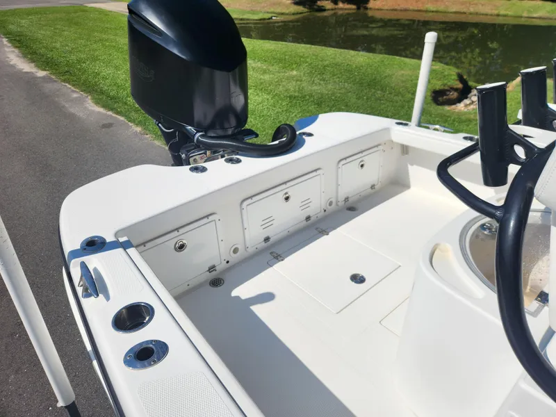 Slide: The Image of 2021 BlackJack 256 Coastal boat interior with motor, rod holders, and storage compartments. - 9