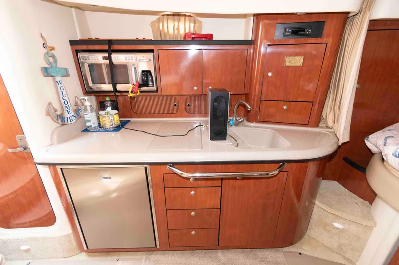Slide: The Image of 2007 Sea Ray 340 Sundancer kitchen with wood cabinets, sink, microwave, and mini-fridge. - 14
