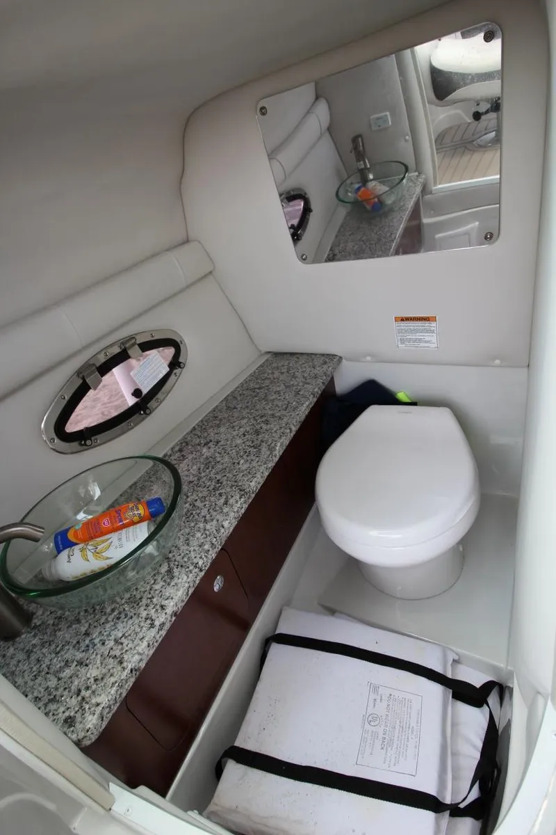 Slide: The Image of 2023 Crownline 270 SS boat bathroom with granite countertop, mirror, and porthole window. - 15