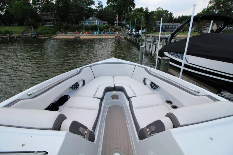 Slide: The Image of 2023 Crownline 270 SS boat interior with white seating, docked by a lakeside. - 16