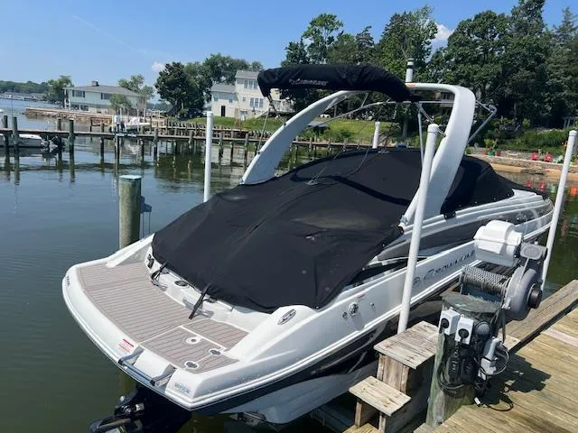 Slide: The Image of 2023 Crownline 270 SS boat docked, covered with black tarp, in a serene marina setting. - 19