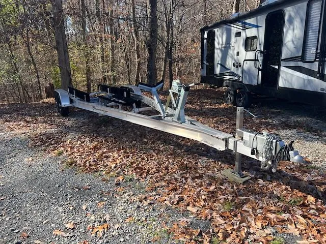 Slide: The Image of Trailer for 2023 Crownline 270 SS boat parked in wooded area near RV. - 23
