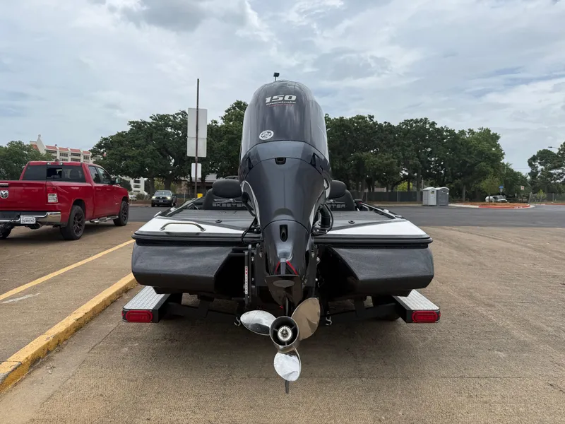 Slide: The Image of 2022 Skeeter ZX 150 boat with outboard motor, parked near a red truck. - 14