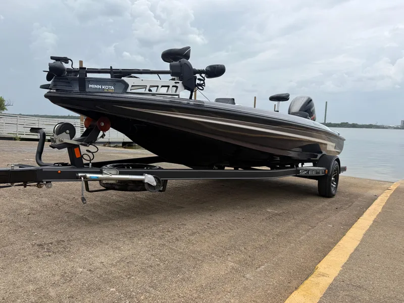 Slide: The Image of 2022 Skeeter ZX 150 boat on trailer by the water, featuring Minn Kota Ultrex motor. - 2