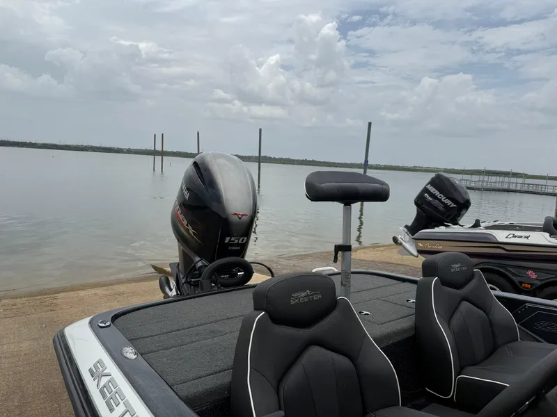 Slide: The Image of 2022 Skeeter ZX 150 boat at a lakeside dock under cloudy skies. - 23