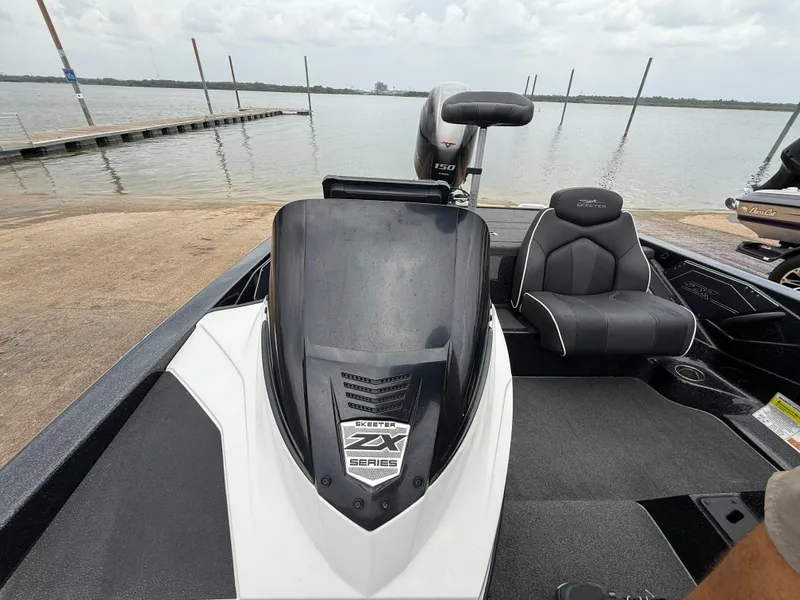 Slide: The Image of 2022 Skeeter ZX 150 boat at a lakeside dock, featuring sleek seating and modern design. - 38