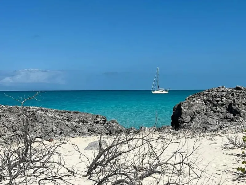 Slide: The Image of Sailboat Island Packet 485, 2004, anchored in turquoise sea, framed by rocky beach. - 17
