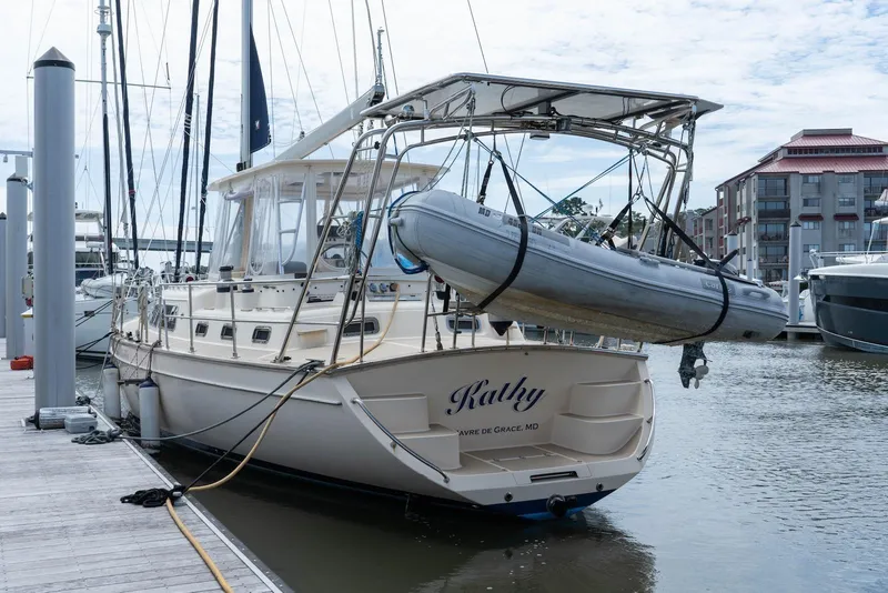 Slide: The Image of Island Packet 485 sailboat from 2004 docked with dinghy, named "Kathy," in a marina. - 2