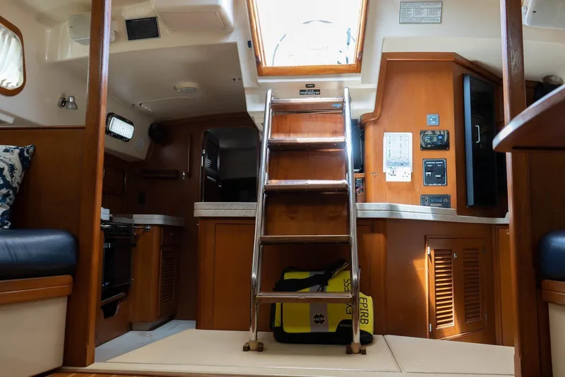 Slide: The Image of Interior of 2004 Island Packet 485 sailboat with wooden cabinetry and ladder access. - 23