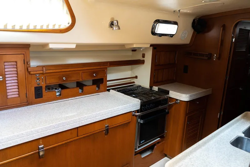 Slide: The Image of 2004 Island Packet 485 yacht interior kitchen with wooden cabinetry and modern appliances. - 28