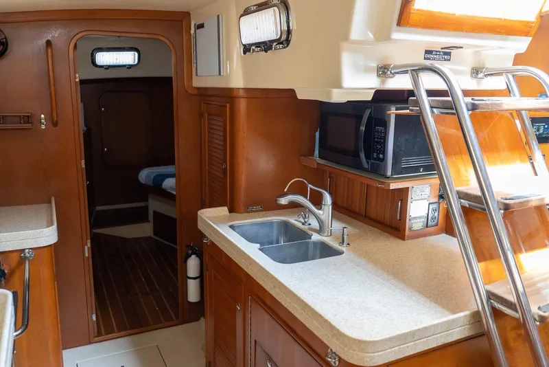 Slide: The Image of Interior of 2004 Island Packet 485 yacht, featuring a modern kitchen and wooden cabinetry. - 29
