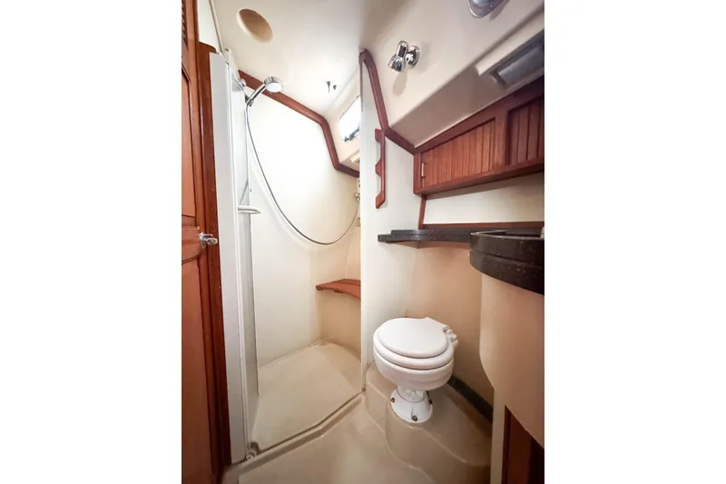Slide: The Image of 2004 Island Packet 485 yacht bathroom with shower, toilet, and wooden cabinetry. - 32
