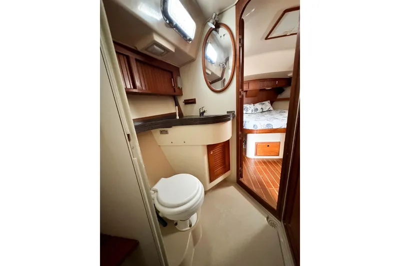 Slide: The Image of 2004 Island Packet 485 yacht bathroom with wooden cabinetry and adjacent bedroom view. - 33