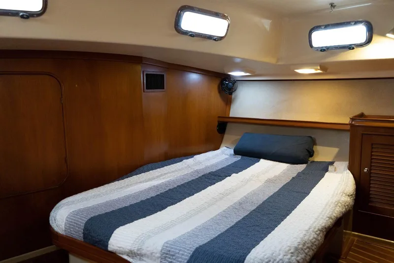Slide: The Image of 2004 Island Packet 485 yacht cabin with cozy bed and wooden interior. - 35