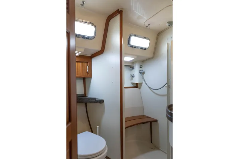 Slide: The Image of 2004 Island Packet 485 yacht bathroom with shower, wooden accents, and porthole windows. - 38