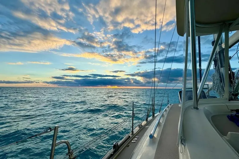 Slide: The Image of Sailing on Island Packet 485, 2004 model, at sunset with vibrant sky and ocean view. - 4