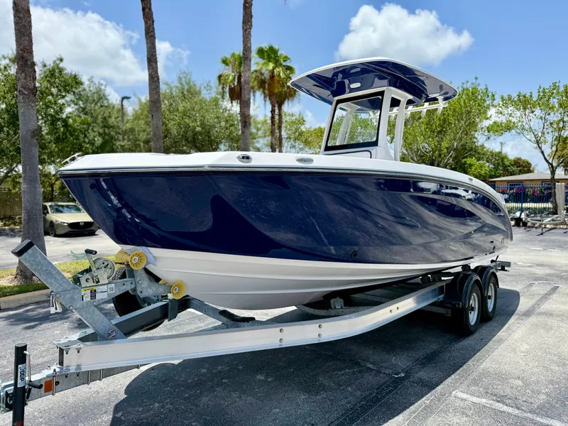 Slide: The Image of 2025 Yamaha Boats 255 FSH Sport H on trailer, parked outdoors under sunny skies. - 2