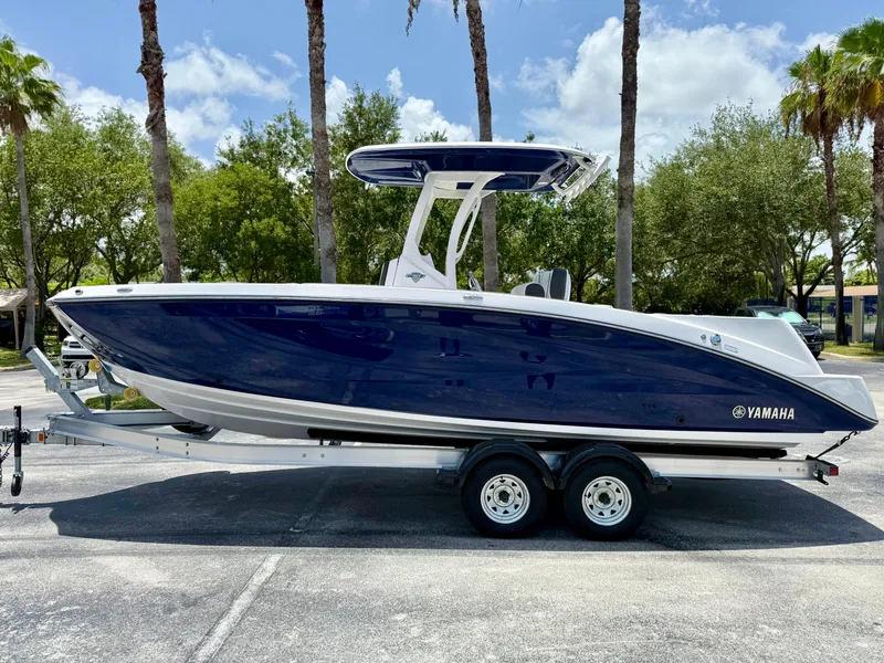 Slide: The Image of 2025 Yamaha Boats 255 FSH Sport H on trailer, parked outdoors under palm trees. - 3