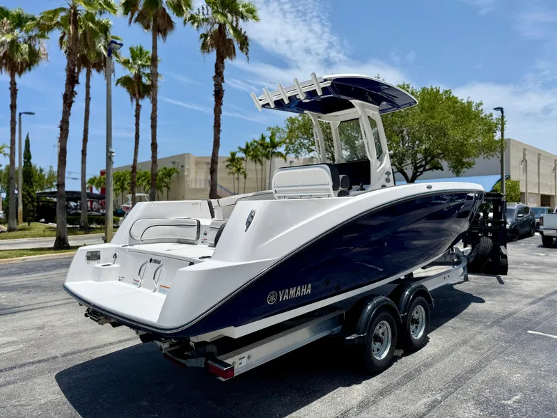 Slide: The Image of 2025 Yamaha Boats 255 FSH Sport H on trailer, parked under palm trees. - 7