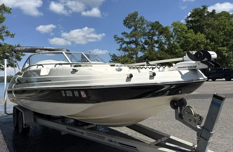 Slide: The Image of 2006 Hurricane SD 237 boat on trailer, parked near a lake with trees in the background. - 3