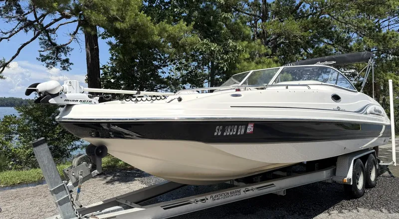 Slide: The Image of 2006 Hurricane SD 237 boat on trailer, parked near a lake with trees in the background. - 6
