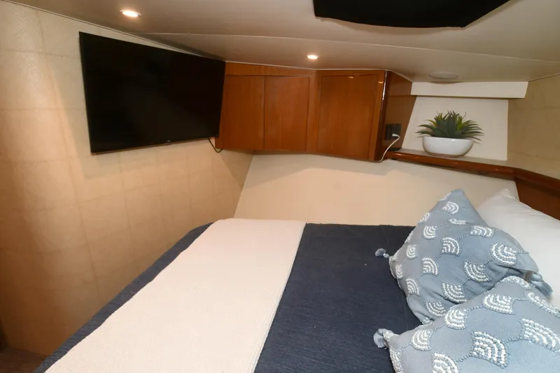 Slide: The Image of Cozy bedroom in 2000 Viking Boats 65 C with TV, wooden cabinets, and decorative pillows. - 6