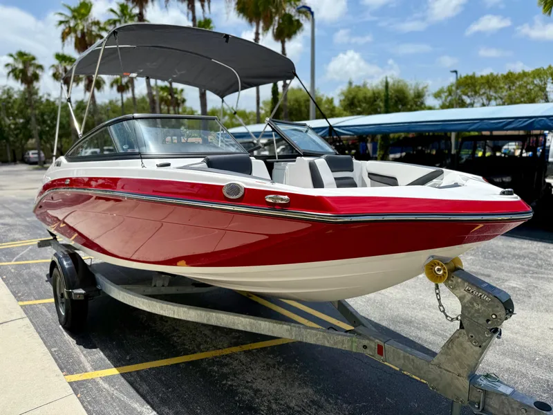 The Image of 2025 Yamaha Boats SX195 in vibrant red on a trailer, parked under sunny skies. - 0