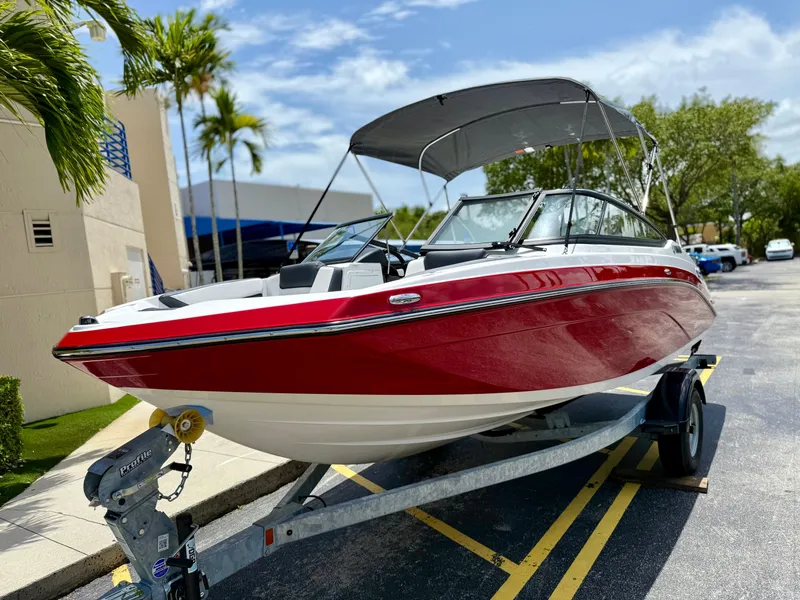 Slide: The Image of 2025 Yamaha Boats SX195 in red on a trailer, parked outdoors. - 2
