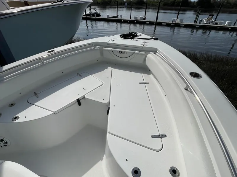 Slide: The Image of 2017 Sea Hunt Ultra 234 boat interior with seating and storage, docked by the water. - 11