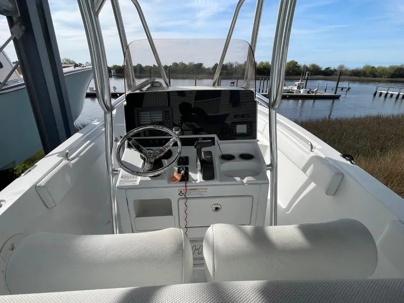 Slide: The Image of 2017 Sea Hunt Ultra 234 boat interior with steering console, docked by a serene waterfront. - 17