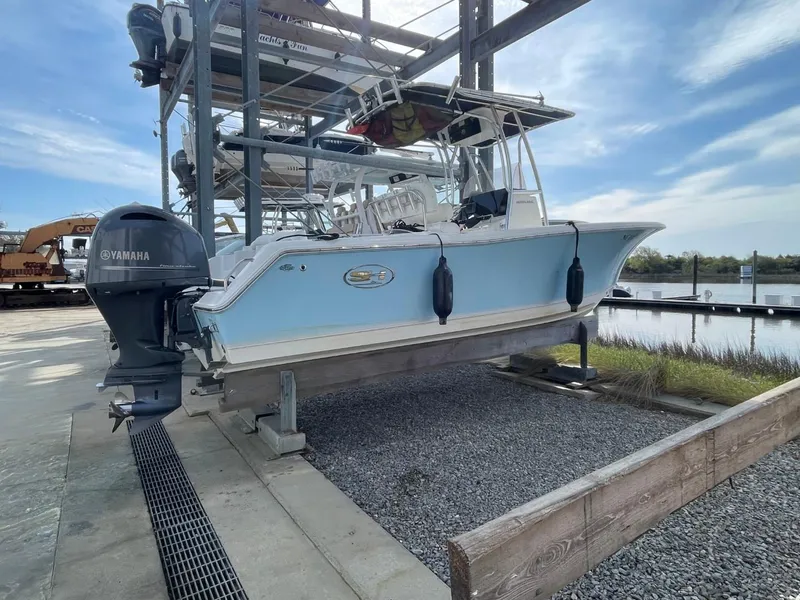 Slide: The Image of 2017 Sea Hunt Ultra 234 boat with Yamaha engine on a lift by the water. - 5