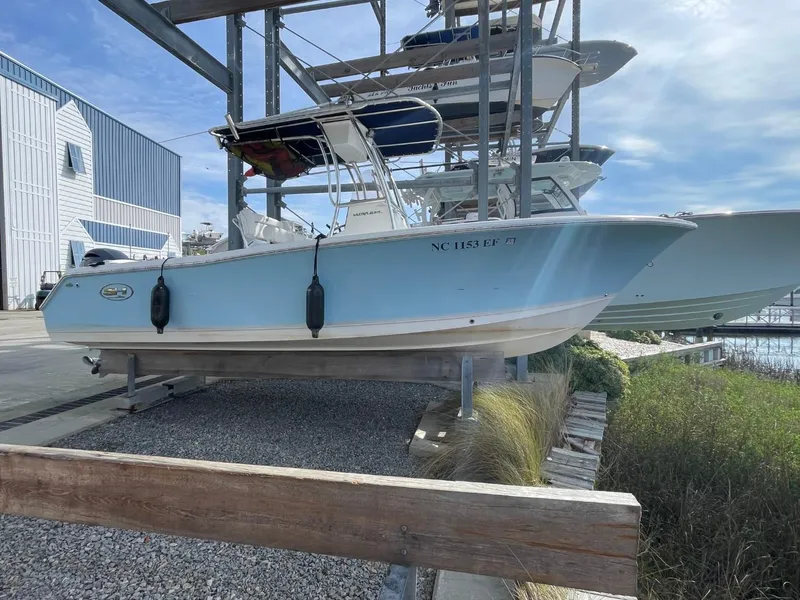 Slide: The Image of 2017 Sea Hunt Ultra 234 boat in dry dock, light blue hull, marina background. - 7