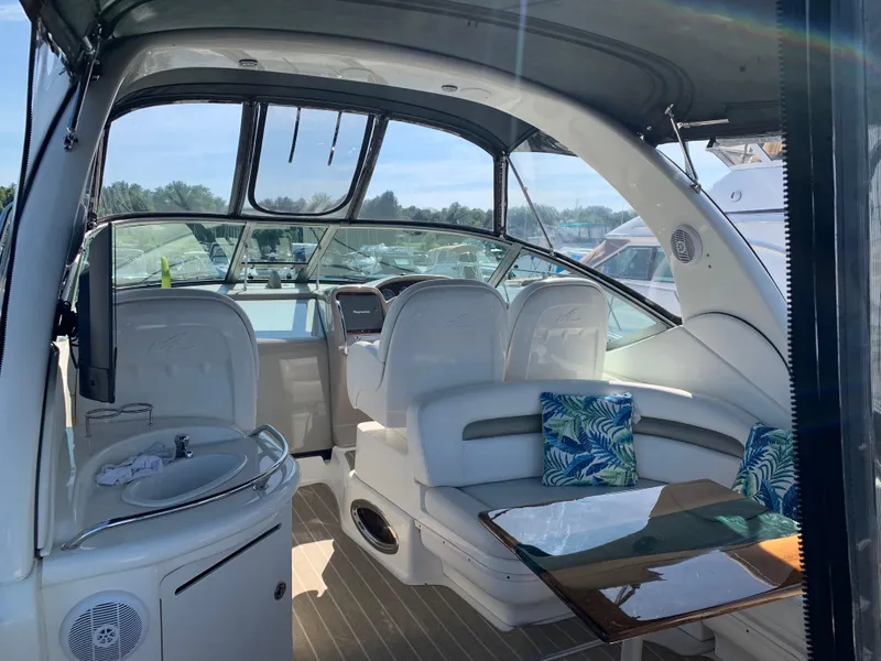 Slide: The Image of 2006 Sea Ray 340 Sundancer interior with seating, table, and helm, under a sunny sky. - 15