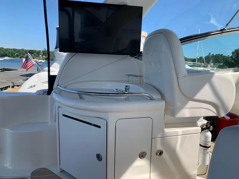 Slide: The Image of 2006 Sea Ray 340 Sundancer cockpit with TV, sink, and seating, docked by a lake. - 25