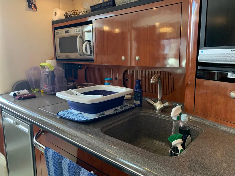 Slide: The Image of 2006 Sea Ray 340 Sundancer kitchen with sink, microwave, and wooden cabinets. - 33