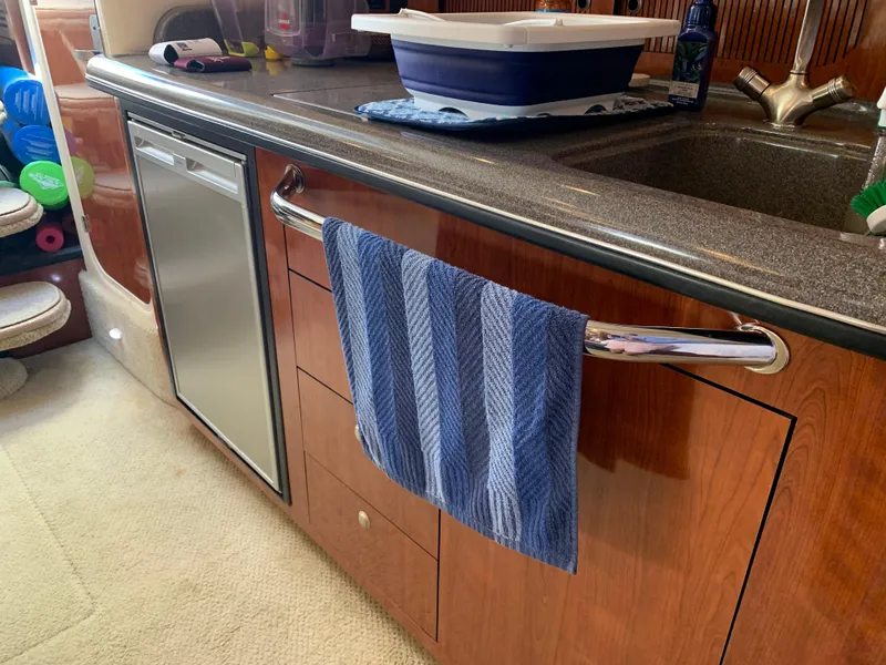 Slide: The Image of 2006 Sea Ray 340 Sundancer galley with wood cabinetry, stainless steel fridge, and blue towel. - 34