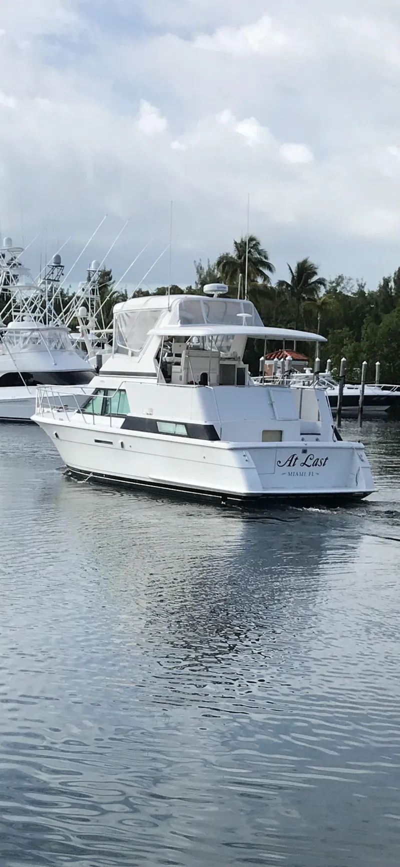 The Image of 1994 Hatteras 42 Cockpit Motor Yacht on calm water, surrounded by trees and other boats. - 0