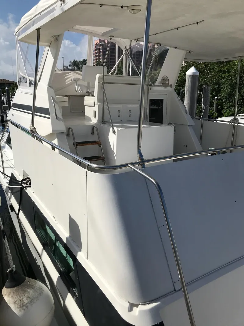 Slide: The Image of 1994 Hatteras 42 Cockpit Motor Yacht docked, featuring spacious deck and seating area. - 13