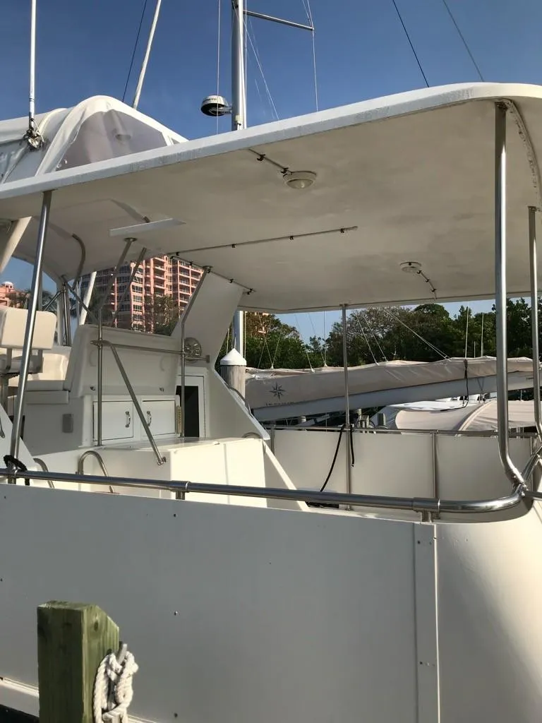 Slide: The Image of 1994 Hatteras 42 Cockpit Motor Yacht docked, featuring spacious deck and canopy. - 15